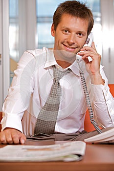 Businessman conversing on landline phone, portrait