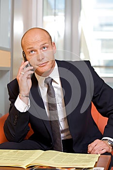 Businessman conversing on mobile phone, looking up photo