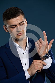 A businessman is correcting the cuff on his shirt before a meeting. A man dressed in a suit.