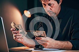 Businessman counting american dollars at office desk