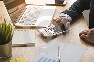 Businessman counting on calculator and reviewing budget.