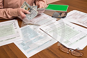 Businessman counting dollars of tax forms