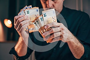 Businessman counting fifty euro banknotes in office while working overtime