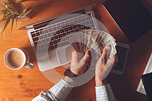 Businessman counting US dollar paper banknotes cash money at office desk