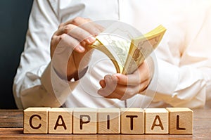 Businessman counts money on the background of the caption Capital. Capitalism, capital increase and influence. Financial photo