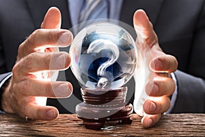 Businessman Covering Crystal Ball With Question Mark