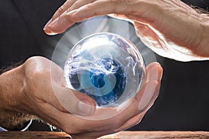 Businessman Covering Crystal Ball With Swirling Smoke