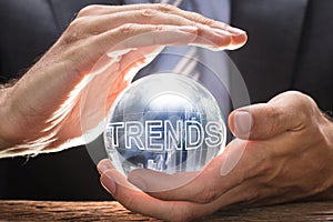 Businessman Covering Crystal Ball With Trends Text And Graphs photo