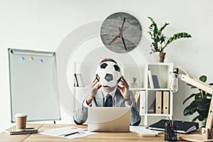 businessman covering face with soccer ball