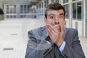 Businessman covering his mouth after making a mistake