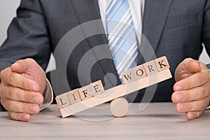 Businessman covering imbalance between life and work on seesaw