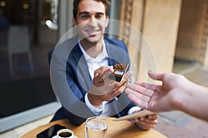 Businessman, credit card and waitress hand for payment or outdoor coffee shop for customer service, transaction or