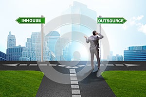 Businessman at crossroads deciding between outsourcing and inhou