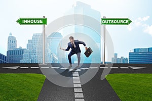 Businessman at crossroads deciding between outsourcing and inhou