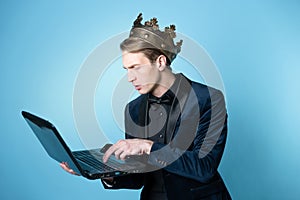 businessman with a crown on his head uses a laptop and a phone.