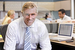 Businessman in cubicle smiling