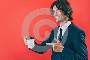 Businessman with a cup of coffee in his hands on a red background