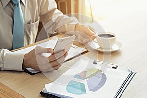 Businessman with a cup of coffee reading his smart phone in a ca