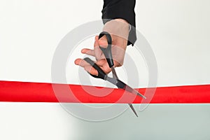 Businessman cutting red ribbon with scissors