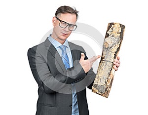 Businessman in a dark suit and glasses holds a log in his hand, pointing at it with his hand, isolated on a white background.