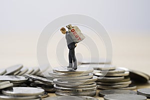 Businessman debtor miniature figure carry big money bag on the top of coins stacking for business consumer burden financial debt photo