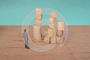 The businessman, deep in thought and surrounded by wooden blocks, pondered the problem and the challenge of development, searching photo
