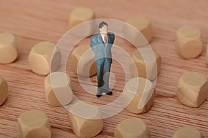 The businessman, deep in thought and surrounded by wooden blocks, pondered the problem and the challenge of development, searching photo