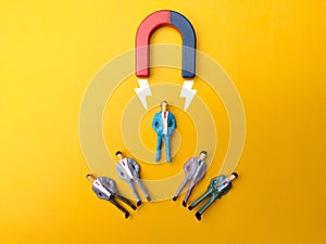 Businessman is demonstrating the power of leadership and magnetism by using a magnet