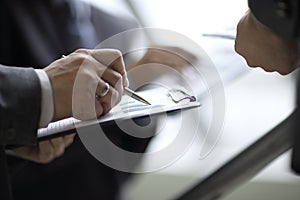 Businessman at desk checking a financial report and pointing at a bar chart with a pen