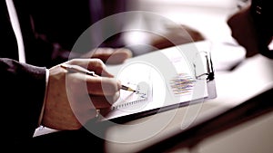 Businessman at desk checking a financial report and pointing at a bar chart with a pen