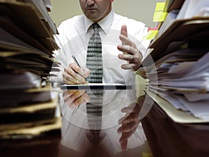 Businessman at Desk with Files Gesturing