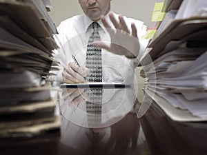 Businessman at Desk with Files Holding up Hand