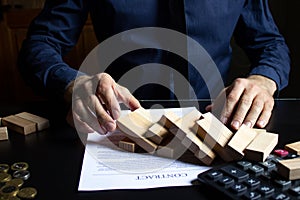 A businessman destroyed a wooden tower by taking out the bottom block of the foundation.Management of risks.