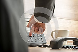 Businessman dialing telephone number on a classical black landline telephone