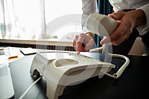 Businessman dialing a telephone number in order to make a phone call.