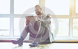 Businessman with digital tablet sitting near window