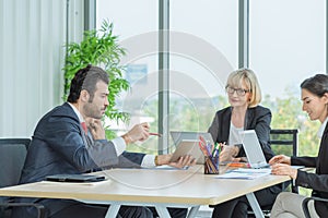 Businessman discussing a new startup project on his tablet to colleagues while meeting at the office. Business Team Meeting