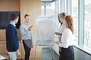 Businessman discussing over whiteboard with colleagues