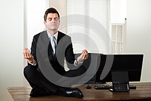 Businessman Doing Meditation In Office