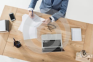 Businessman doing paperwork at workplace with laptop in office