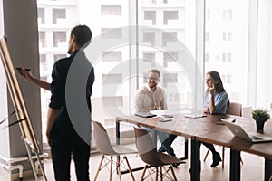 Businessman doing presentation, using whiteboard, explaining to colleagues