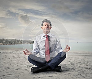 Businessman doing yoga at the sea side