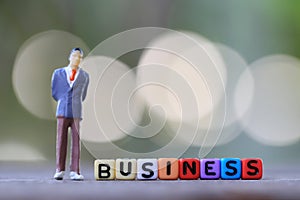 Businessman doll standing beside textbox of Business.
