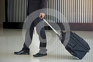 Businessman drag luggage or suitcase walking to the hotel lobby