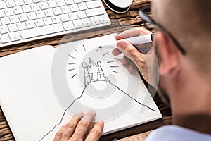 Businessman Drawing The Figures Giving High Five On Notebook