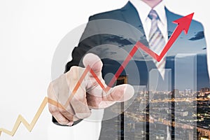 Businessman drawing a rising up arrow by finger, representing business growth