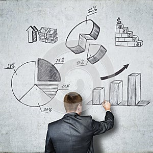 Businessman draws on concrete wall of the business and financial figures. Business concept
