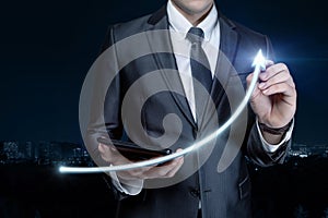 Businessman draws a sharp rise in the form of an arrow on a blurred background