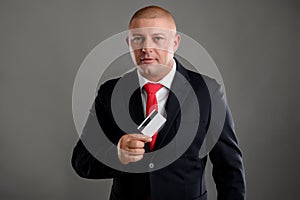 Businessman dressed in black suit is showing his credit card