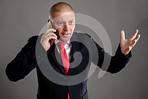 Businessman dressed in black suit talking on the phone he starts to gesticulate with his hand around nervously